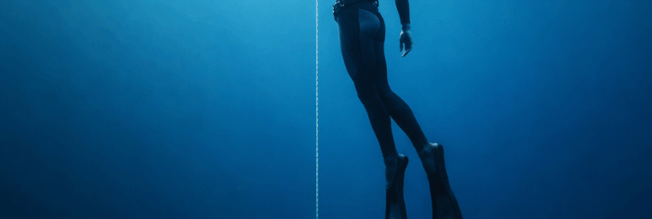 Freitaucher hängt entspannt an einer Abstiegslinie im offenen Ozean beim Freediving, während der Bloodshift-Mechanismus den Körper vor Druck schützt.