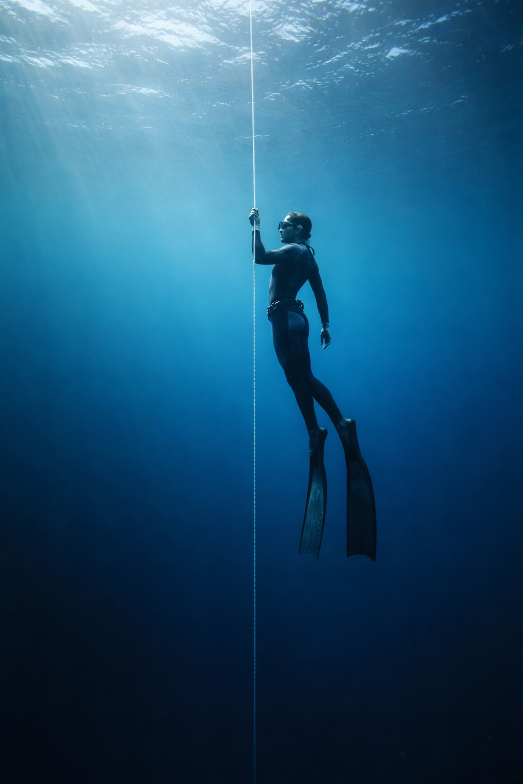 Freitaucher hängt entspannt an einer Abstiegslinie im offenen Ozean beim Freediving, während der Bloodshift-Mechanismus den Körper vor Druck schützt.