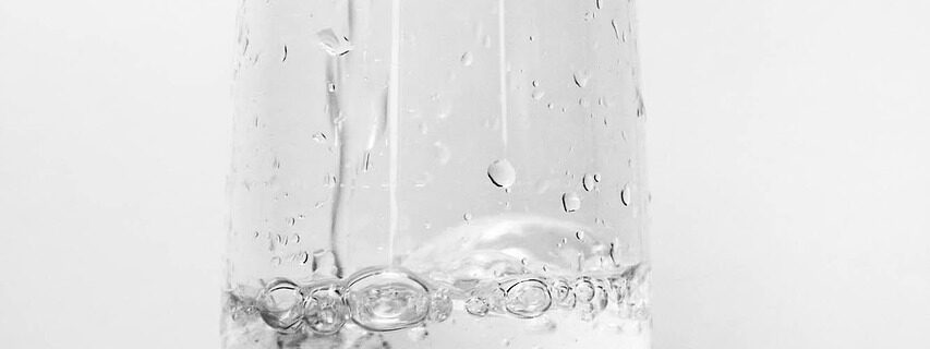 Glas mit Wasser und Limettenscheibe zur Hydration vor dem Freediving, realistisches Setting, erfrischend und klar